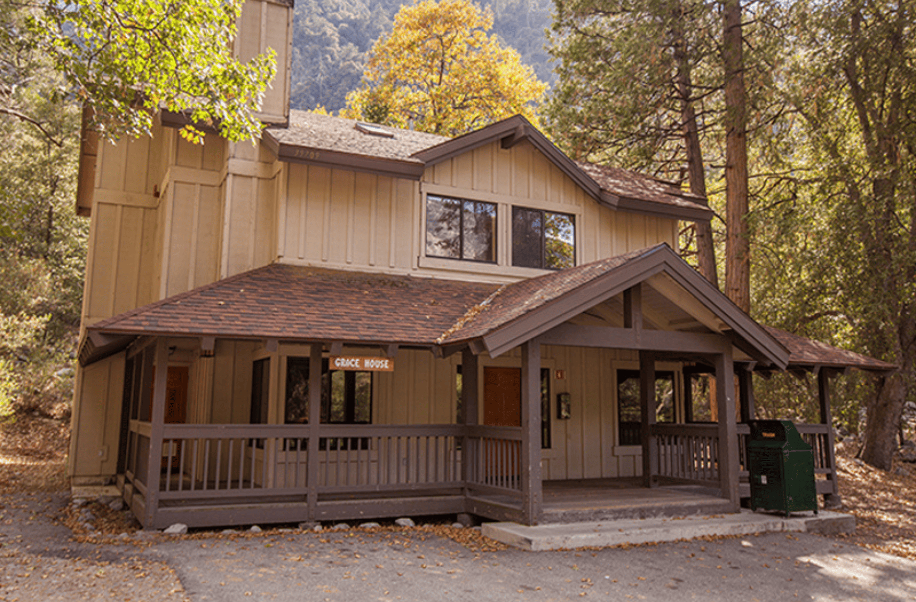 Large house in the woods with two stories and brown exterior